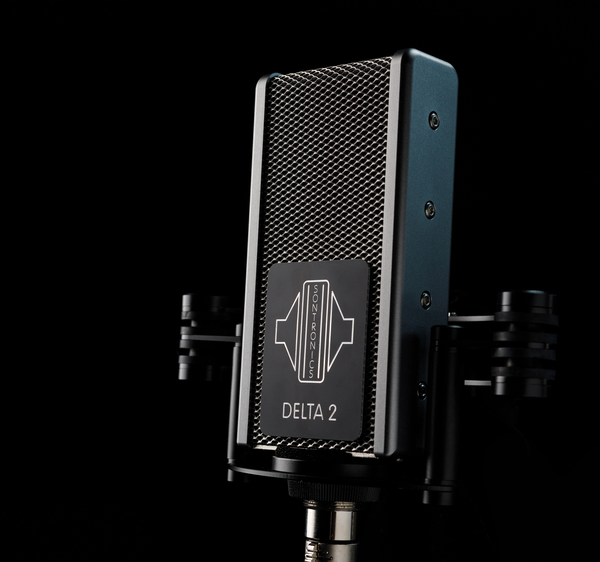 Image on black background with moody lighting showing Sontronics Delta 2 microphone in its shockmoung facing slightly to the left