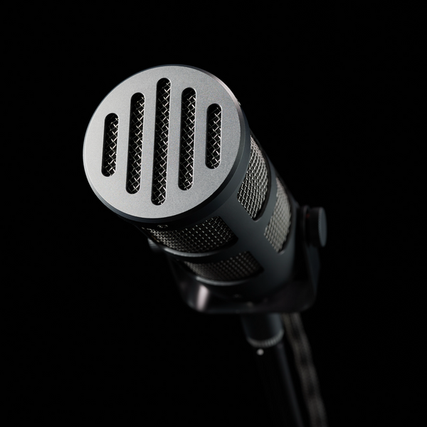 An image on black background showing a Sontronics Podcast Pro microphone in Cosmic grey coming out of the shadow and facing towards us with its vintage-styled grille in the foreground
