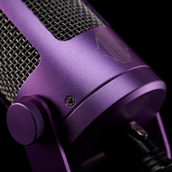 A close-up image on black background of a Sontronics Podcast Pro microphone in purple, showing the rear connected to an XLR cable and also showing the side bracket, thumbscrew, purple body casing and the stainless steel grille