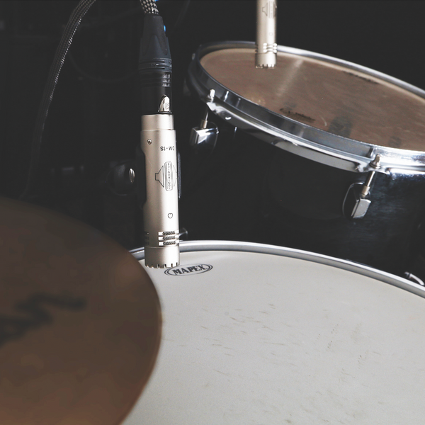 An image showing a silver-coloured Sontronics DM-1S microphone pointing towards a snare drum with a DM-1T microphone mounted over a tom tom in the background and a glimpse of a Zildjian cymbal in the foreground