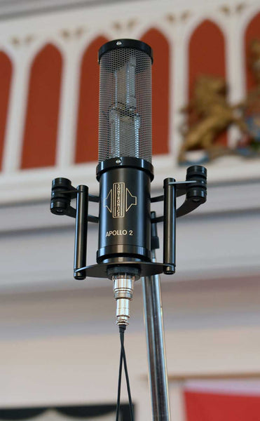 An image of the Sontronics Apollo 2 microphone in its shockmount cradle suspended high up on a mic stand in what appears to be a church setting